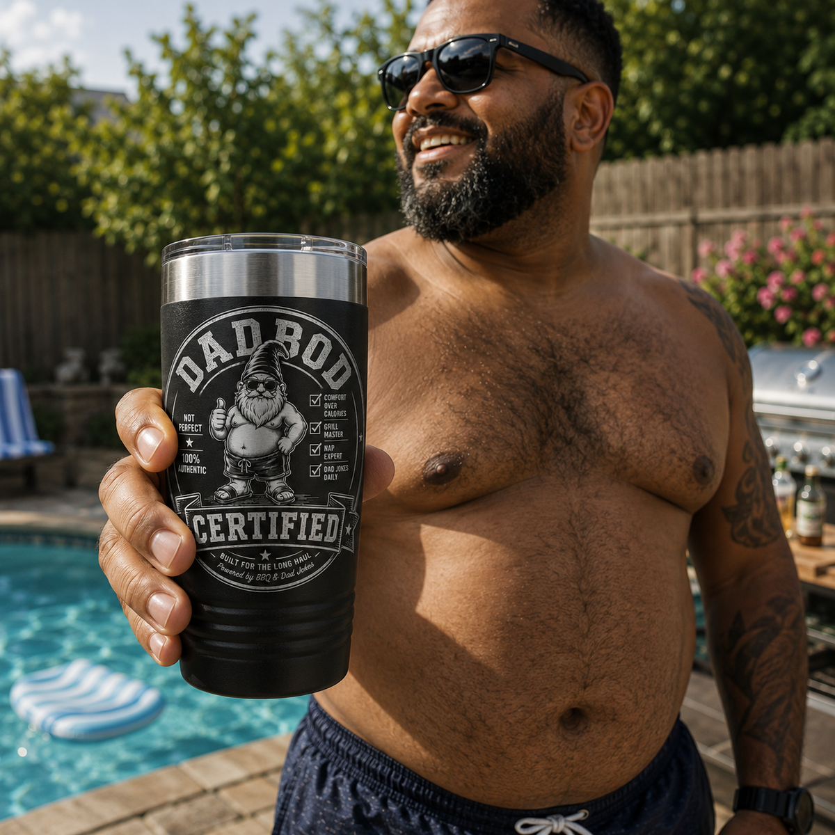 Dad holding black Dad Bod Certified engraved tumbler beside a backyard swimming pool
